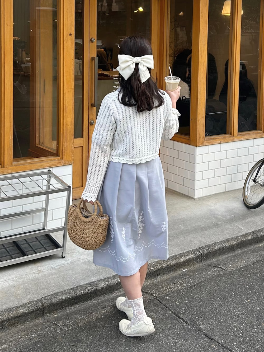 ベージュ系のかごバッグ、ホワイト系のカーディガン/ボレロ、ブルー系のシャツワンピースを着用したレディースの春コーディネートの2枚目の写真