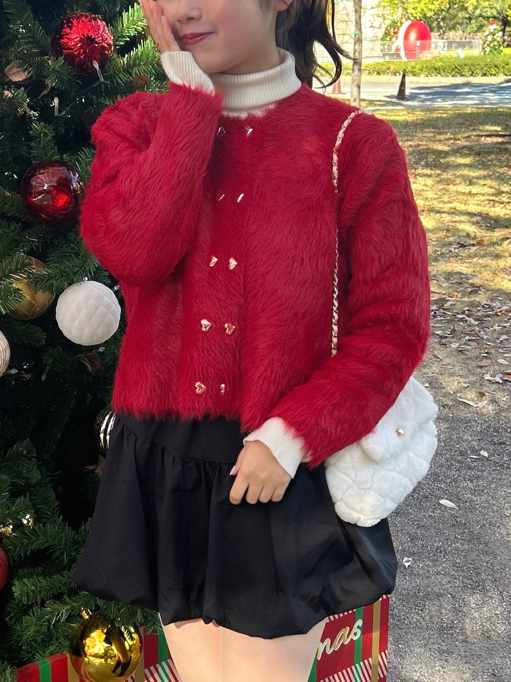 レッド系のカーディガン/ボレロ、ホワイト系のニット/セーター、ブラック系のスカートを着用したレディースの秋コーディネートの3枚目の写真