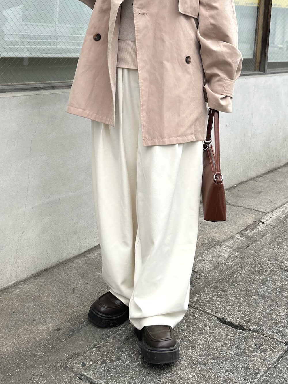 ベージュ系のトレンチコート、ベージュ系のニット/セーター、ホワイト系のスラックスを着用したレディースの春コーディネートの4枚目の写真