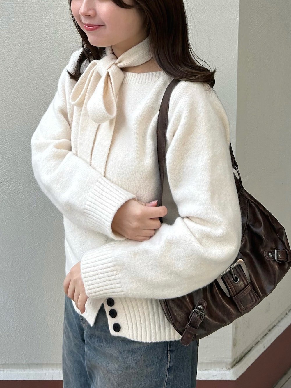 ホワイト系のニット/セーター、ブルー系のデニムパンツ、ブラウン系のブーツを着用したレディースの冬コーディネートの2枚目の写真