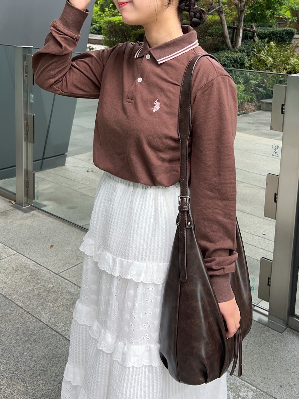 ブラウン系のポロシャツ、ホワイト系のスカート、ブラウン系のショルダーバッグを着用したレディースの秋コーディネートの2枚目の写真