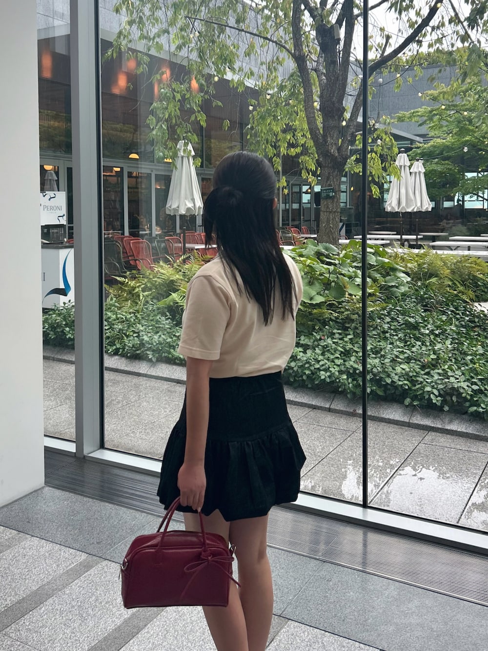 ブラック系のスカート、レッド系のボストンバッグ、ブラック系のパンプスを着用したレディースの夏コーディネートの3枚目の写真