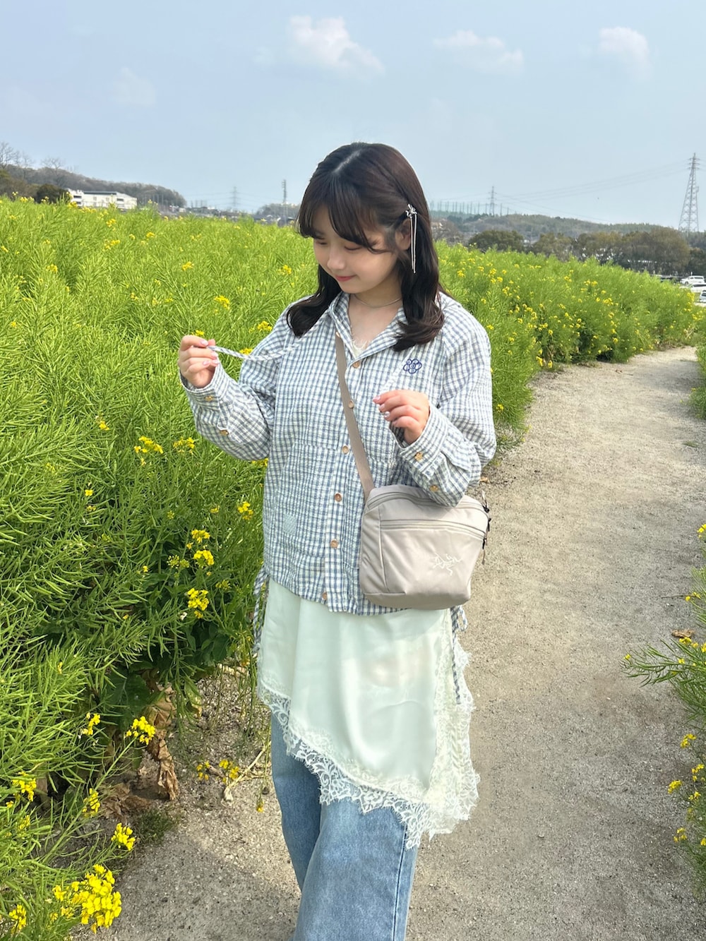 ベージュ系のブルゾン、ブルー系のデニムパンツ、ホワイト系のワンピースを着用したレディースの春コーディネートの3枚目の写真