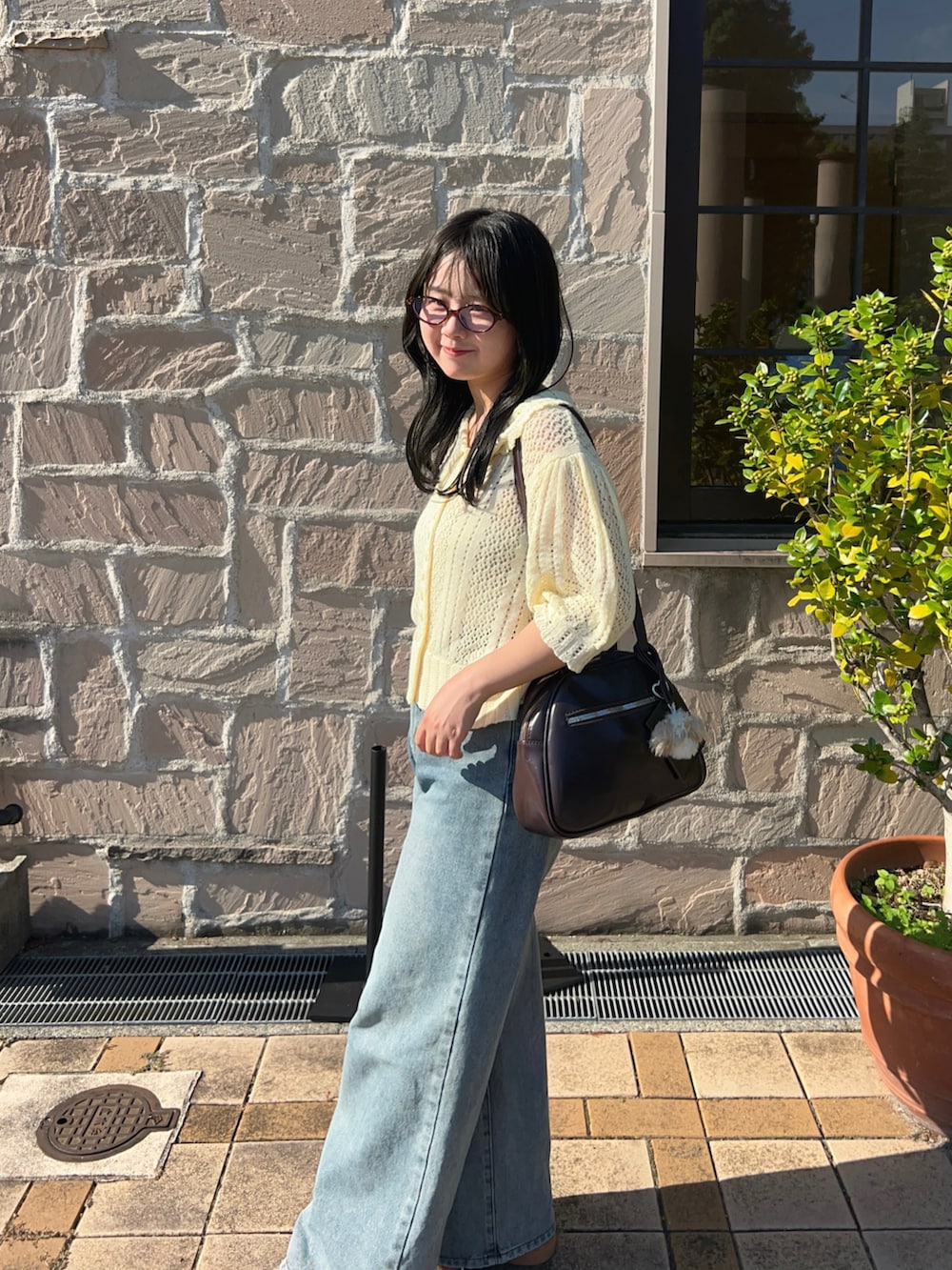 イエロー系のニット/セーター、ブルー系のデニムパンツ、ブラウン系のスニーカーを着用したレディースの夏コーディネートの3枚目の写真