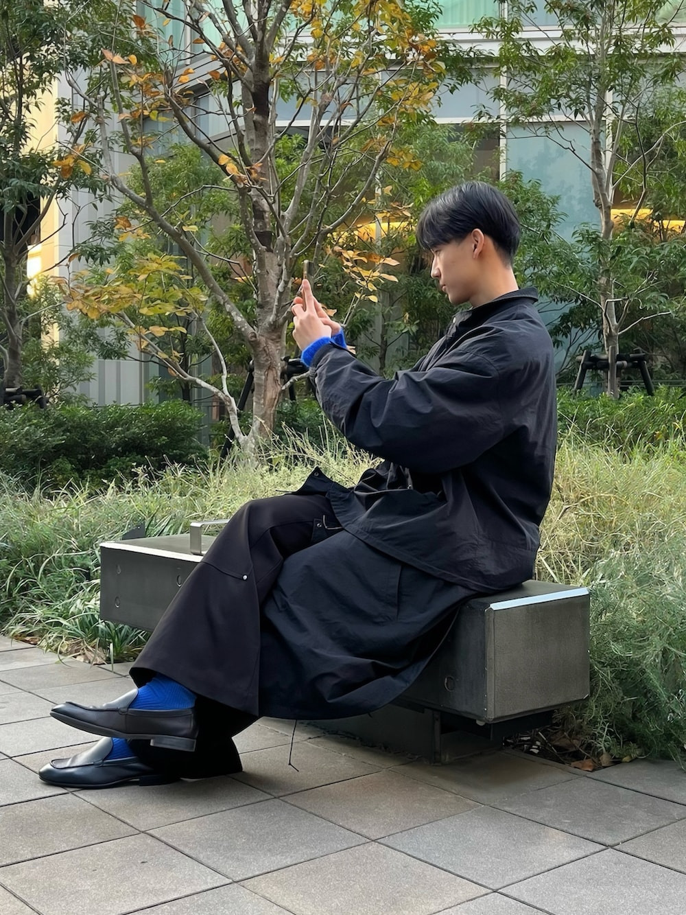 ブラック系のモッズコート、ブラック系のスラックス、ブルー系のニット/セーターを着用したメンズの秋コーディネートの2枚目の写真