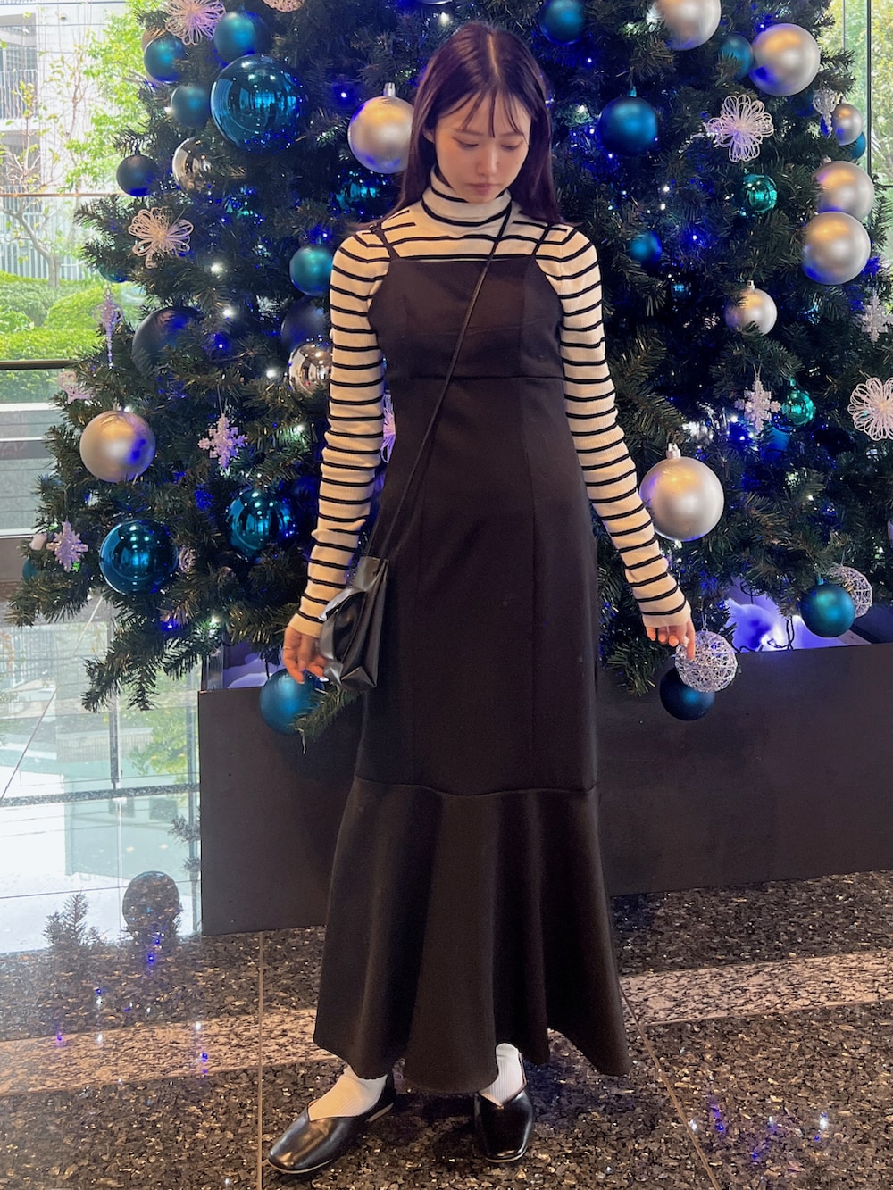 ブラック系のワンピース、ブラック系のパンプス、ブラック系のショルダーバッグを着用したレディースの秋コーディネートの2枚目の写真