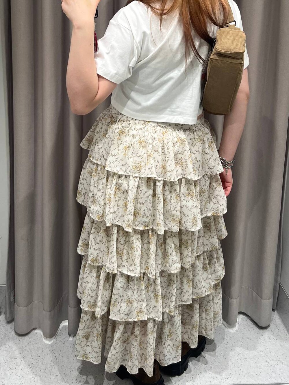 ベージュ系のスカート、ホワイト系のポロシャツ、ブラウン系のモカシン/デッキシューズを着用したレディースの夏コーディネートの3枚目の写真