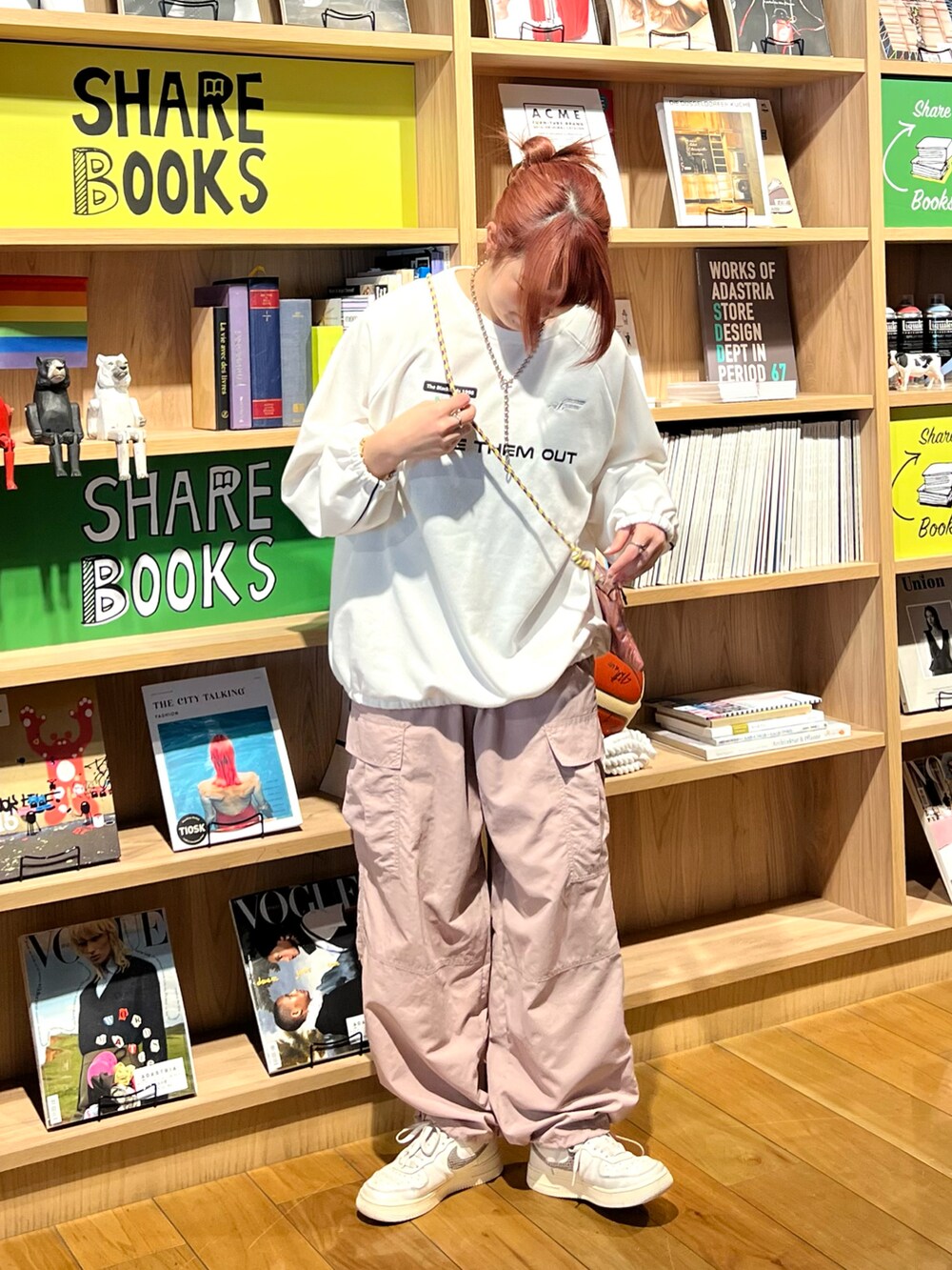 ピンク系のカーゴパンツ、ピンク系のショルダーバッグ、ホワイト系のスウェットを着用したレディースの春コーディネートの2枚目の写真