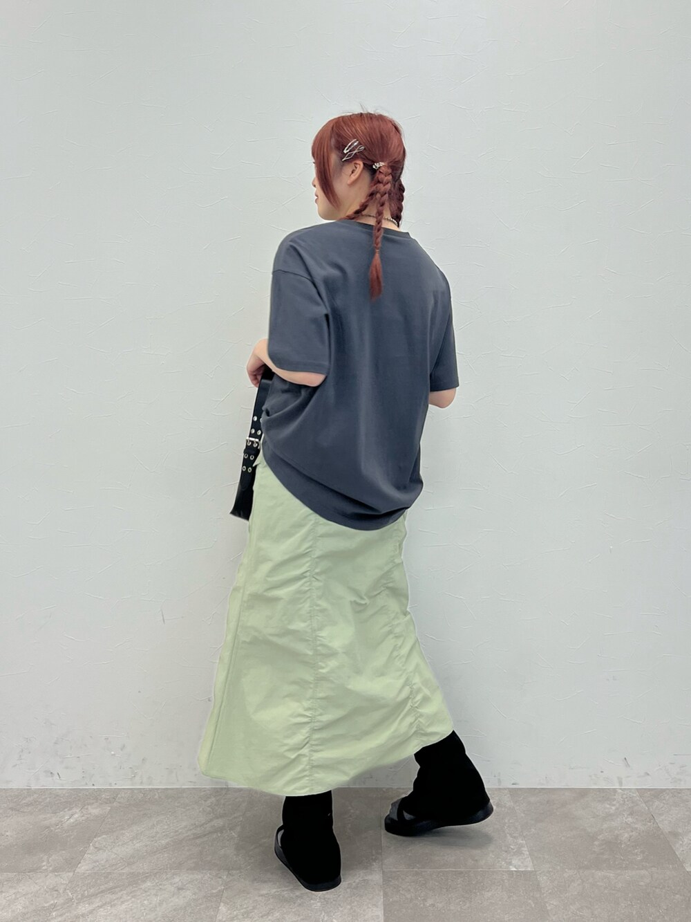 グレー系のTシャツ/カットソー、グリーン系のスカート、ブラック系のサンダルを着用したレディースの春コーディネートの2枚目の写真