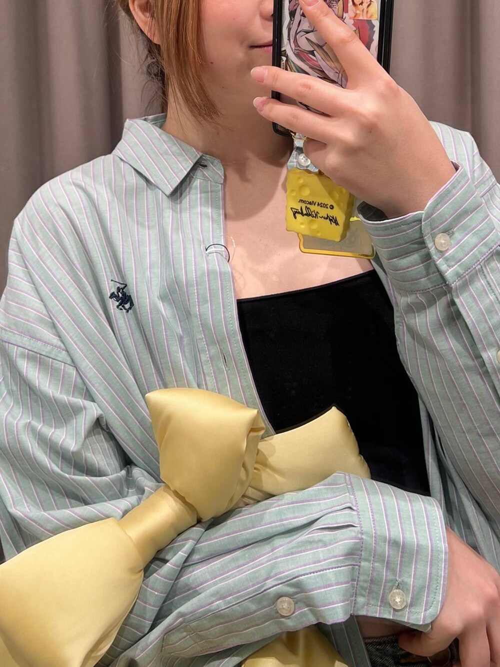 ブルー系のデニムパンツ、イエロー系のハンドバッグ、ブラック系のキャミソールを着用したレディースの春コーディネートの2枚目の写真