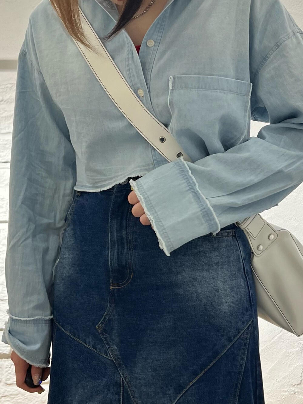 ブルー系のデニムスカート、ブルー系のシャツ/ブラウス、ホワイト系のショルダーバッグを着用したレディースの夏コーディネートの5枚目の写真