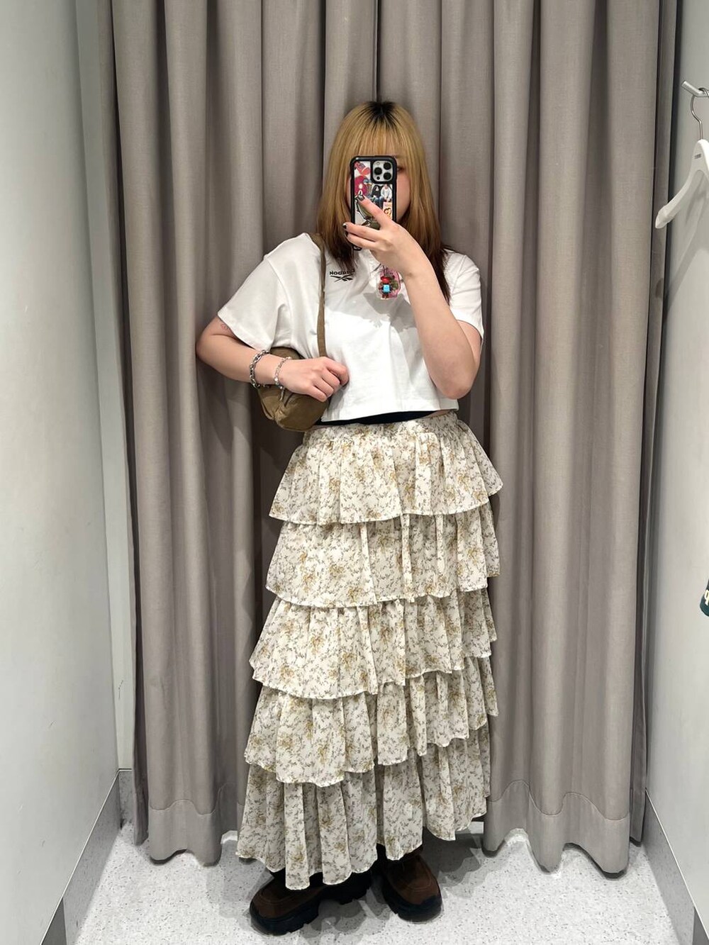 ベージュ系のスカート、ホワイト系のポロシャツ、ブラウン系のモカシン/デッキシューズを着用したレディースの夏コーディネートの4枚目の写真