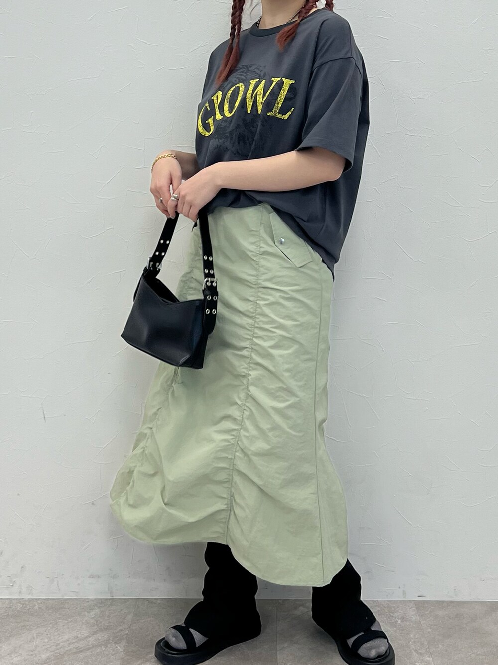 グレー系のTシャツ/カットソー、グリーン系のスカート、ブラック系のサンダルを着用したレディースの春コーディネートの3枚目の写真