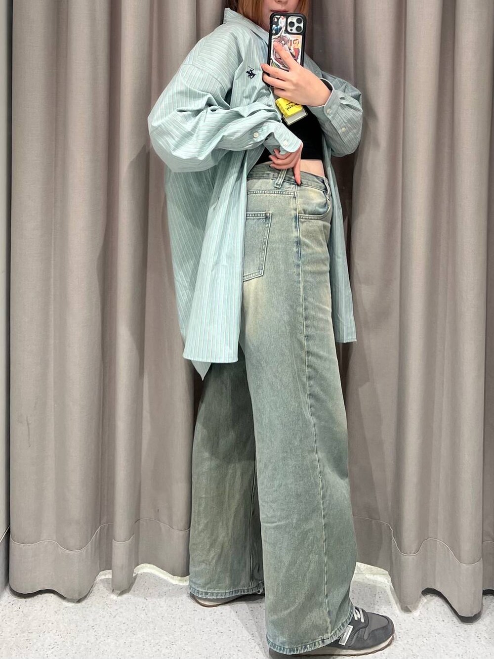 ブルー系のデニムパンツ、イエロー系のハンドバッグ、ブラック系のキャミソールを着用したレディースの春コーディネートの3枚目の写真