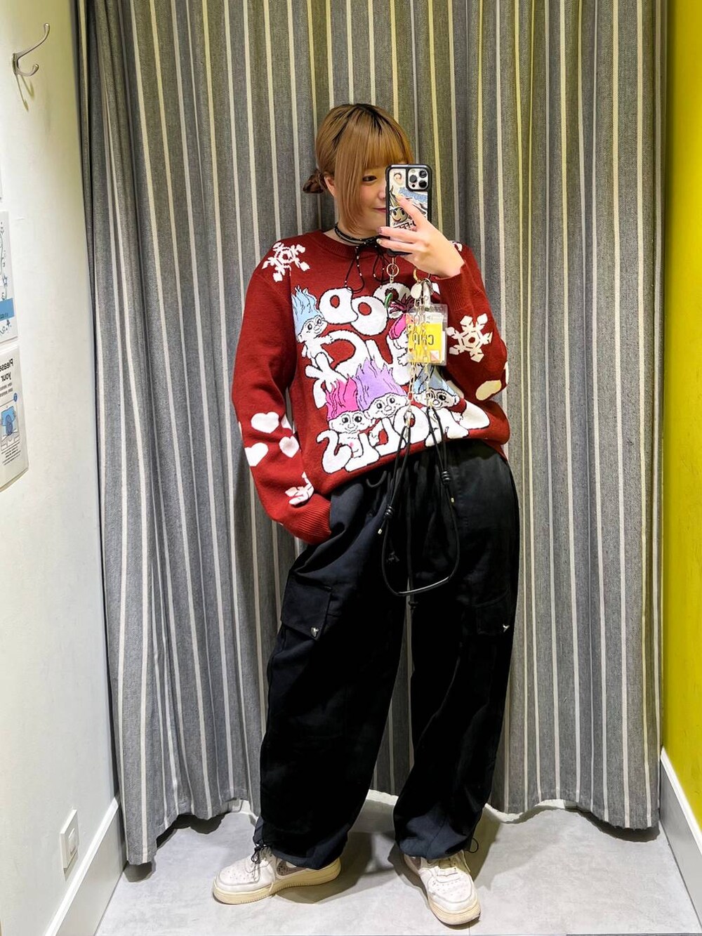 ブラック系のカーゴパンツ、レッド系のニット/セーター、ブラック系のスマホグッズを着用したレディースの秋コーディネートの4枚目の写真