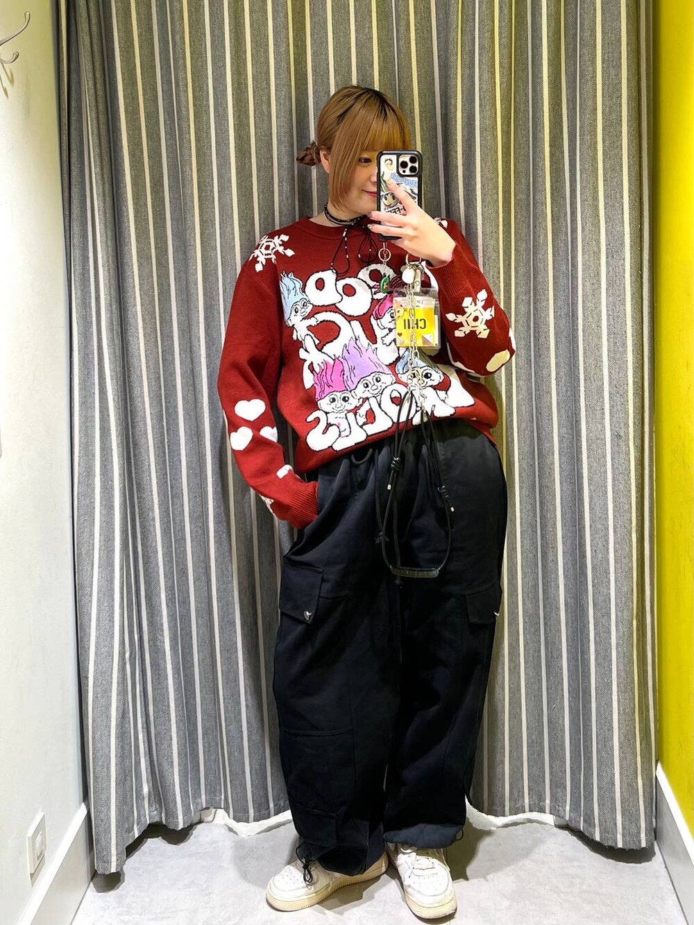 ブラック系のカーゴパンツ、レッド系のニット/セーター、ブラック系のスマホグッズを着用したレディースの秋コーディネートの2枚目の写真