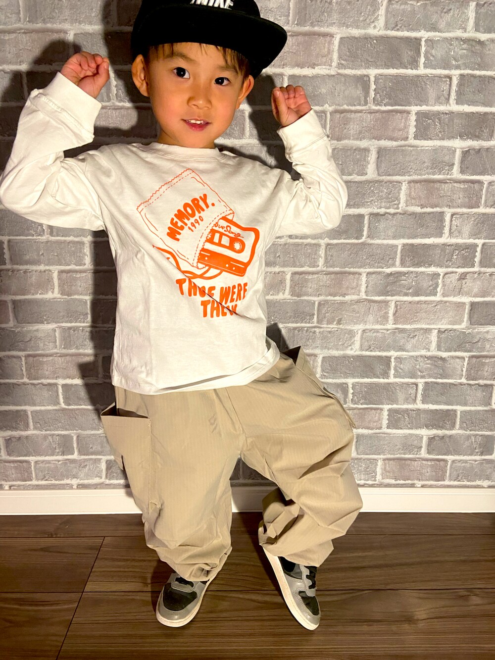 ホワイト系のTシャツ/カットソー、オレンジ系のカーゴパンツを着用したキッズの冬コーディネートの2枚目の写真