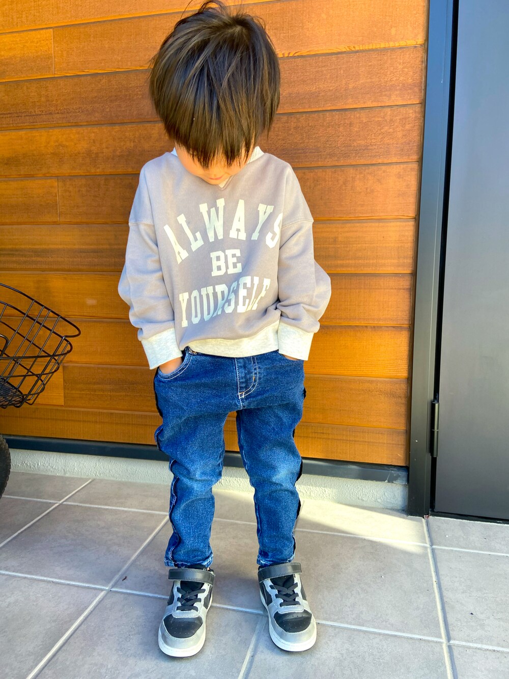 ブルー系のデニムパンツ、グレー系のスニーカー、ブラウン系のスウェットを着用したキッズの秋コーディネートの2枚目の写真