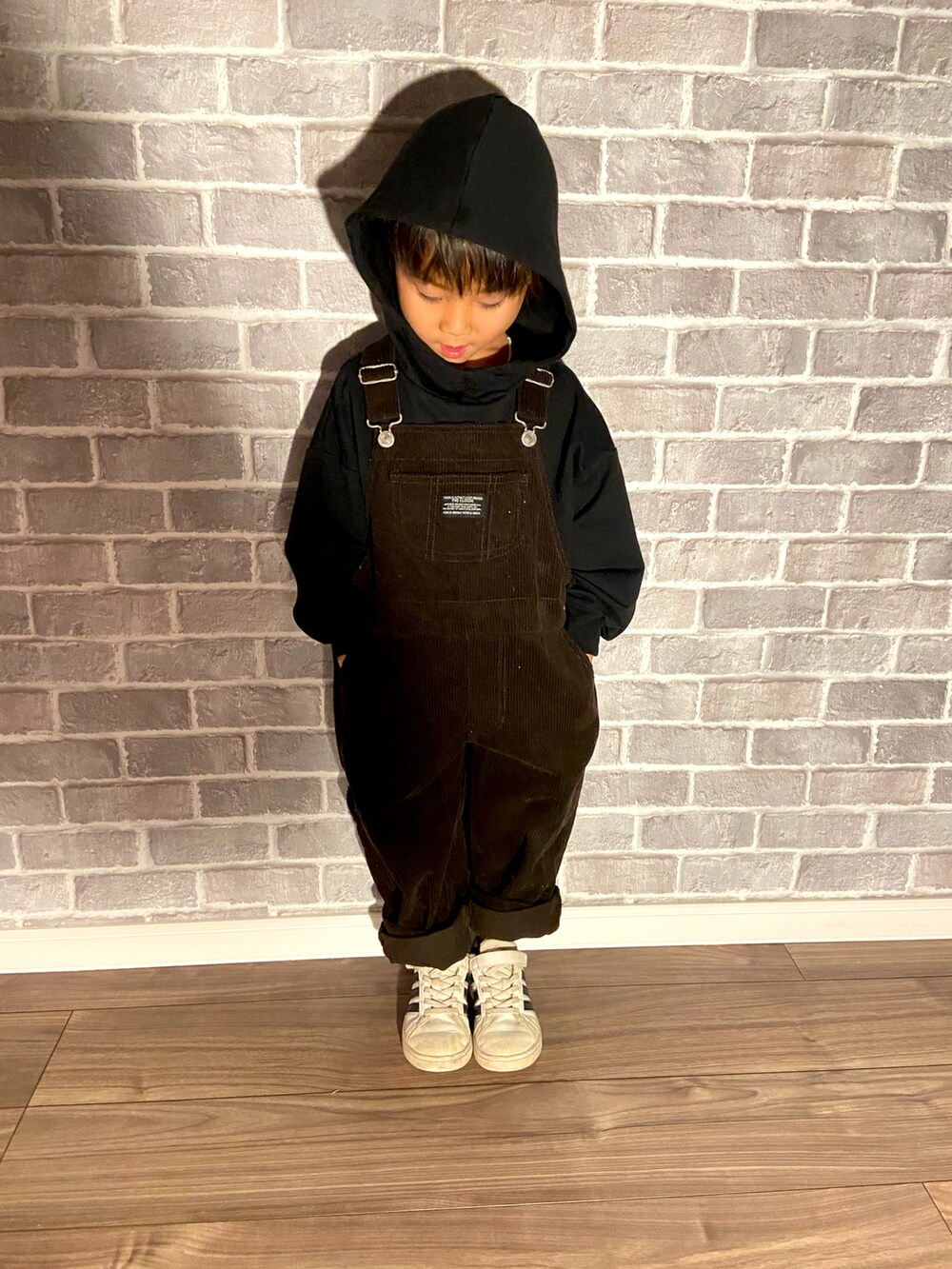 ブラック系のスウェット、ブラウン系のサロペット/オーバーオールを着用したキッズの冬コーディネートの2枚目の写真