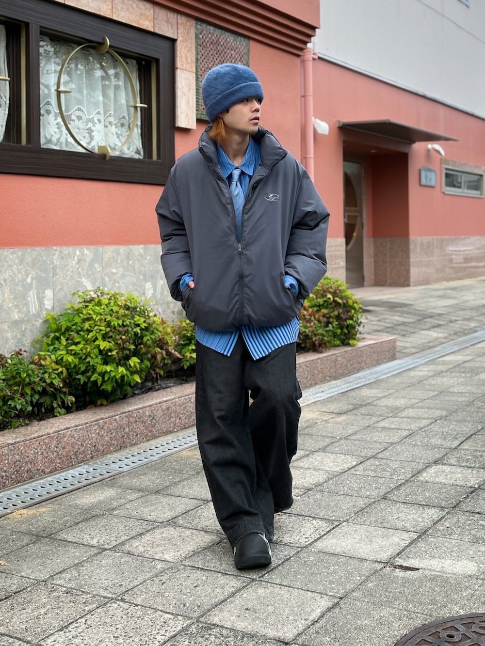 グレー系のダウンジャケット/コート、ブラック系のデニムパンツ、ブルー系のシャツ/ブラウスを着用したメンズの秋コーディネートの2枚目の写真