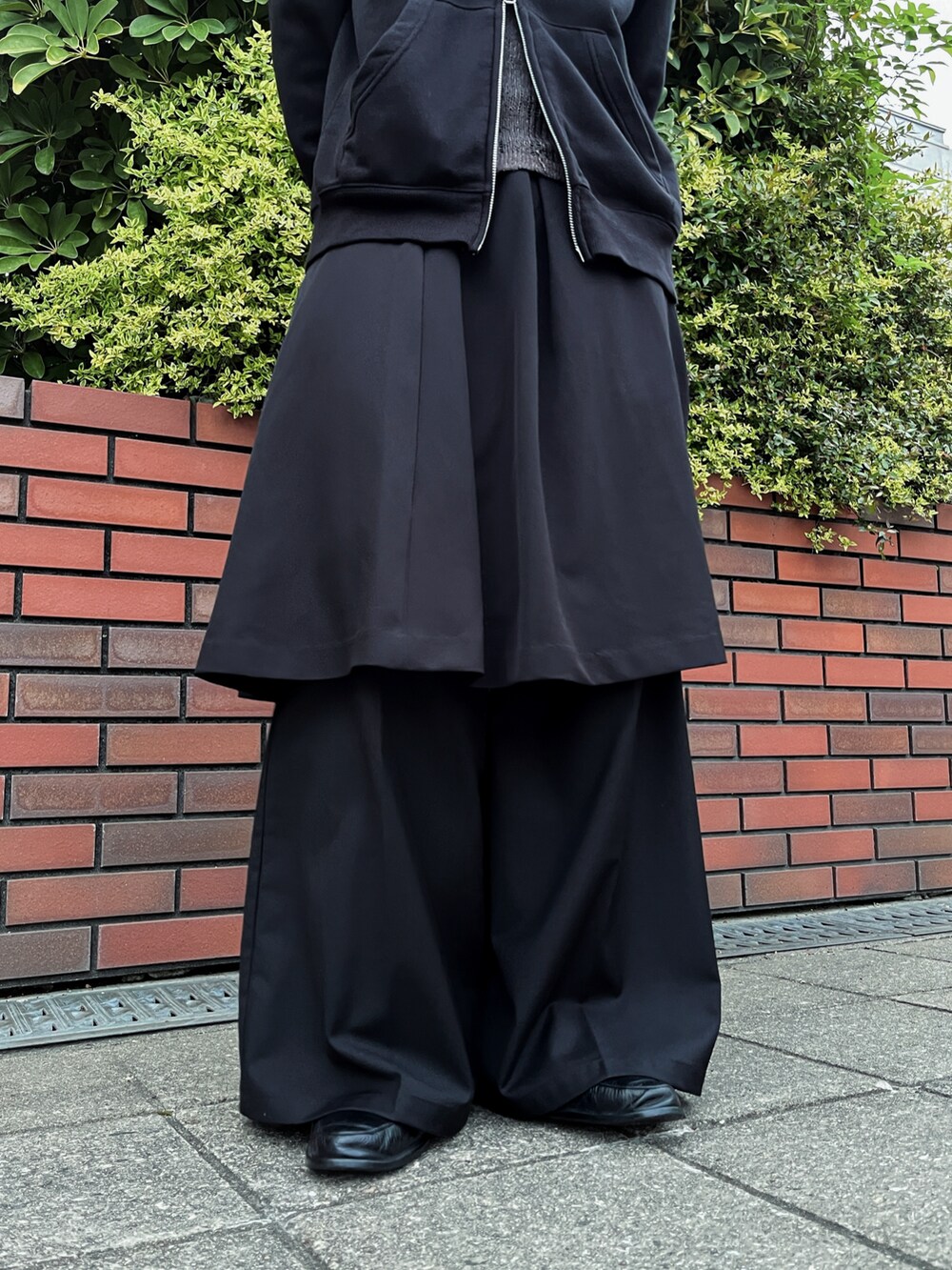 ブラック系のパーカー、ブラック系のスカート、ブラック系のスラックスを着用したメンズの夏コーディネートの3枚目の写真