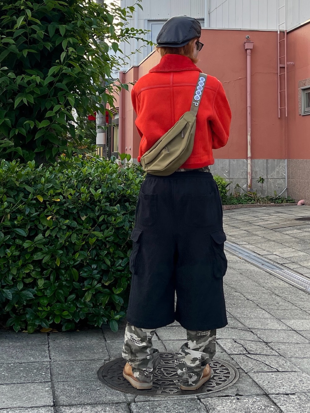 レッド系のブルゾン、ブラック系のスウェットパンツ、グリーン系のサングラスを着用したメンズの秋コーディネートの2枚目の写真