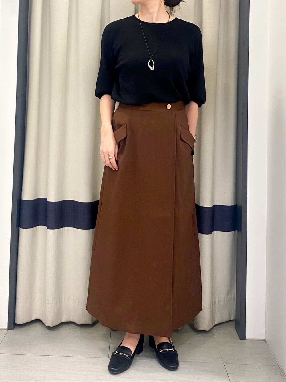 ブラック系のニット/セーター、ブラウン系のスカート、ブラック系のトートバッグを着用したレディースの夏コーディネートの4枚目の写真