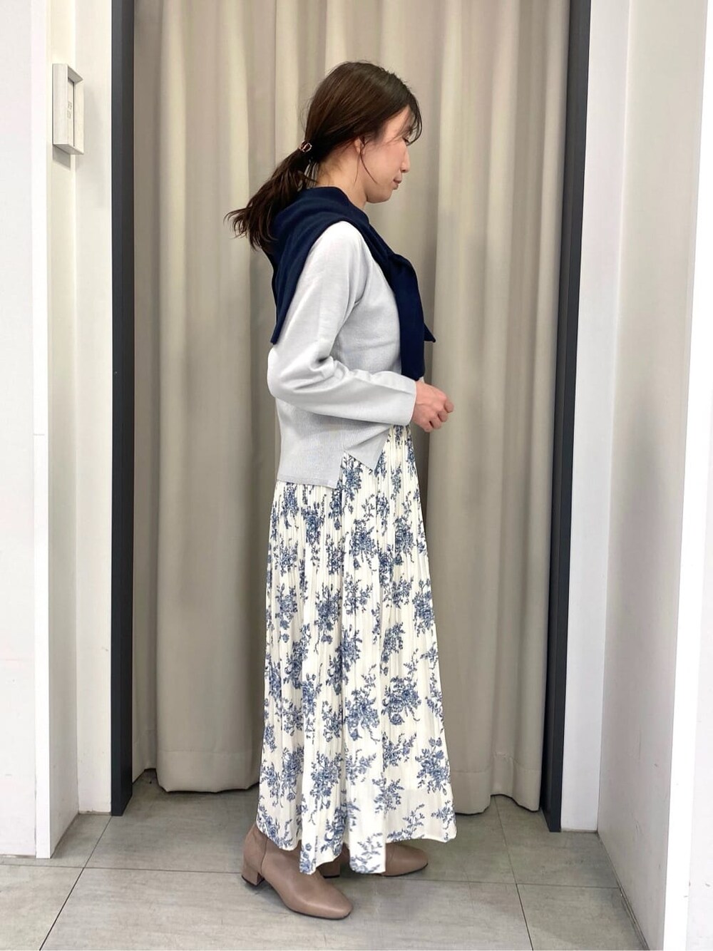 グレー系のニット/セーター、ブルー系のカーディガン/ボレロ、ホワイト系のスカートを着用したレディースの冬コーディネートの2枚目の写真
