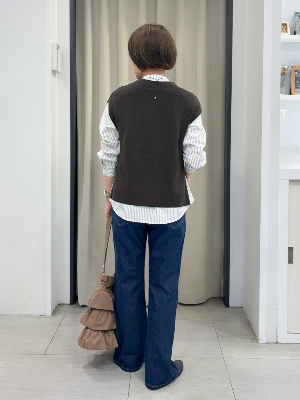 ブルー系のデニムパンツ、グレー系のパンプス、ゴールド系のネックレスを着用したレディースの秋コーディネートの3枚目の写真