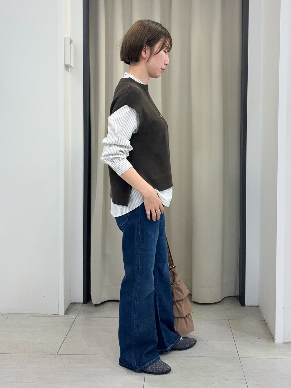 ブルー系のデニムパンツ、グレー系のパンプス、ゴールド系のネックレスを着用したレディースの秋コーディネートの2枚目の写真