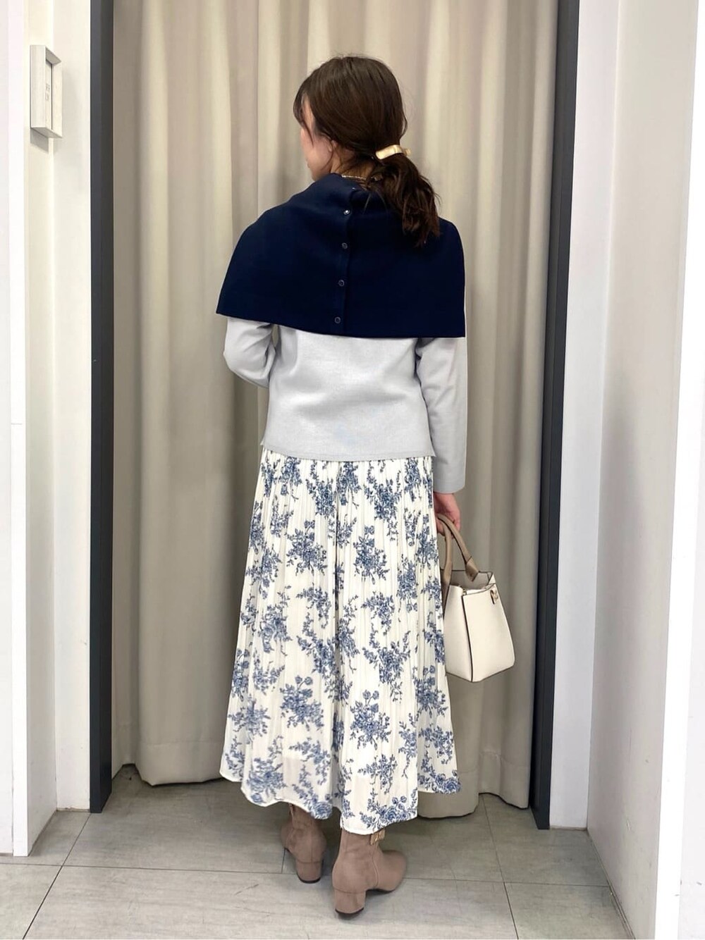 グレー系のニット/セーター、ブルー系のカーディガン/ボレロ、ホワイト系のスカートを着用したレディースの冬コーディネートの3枚目の写真