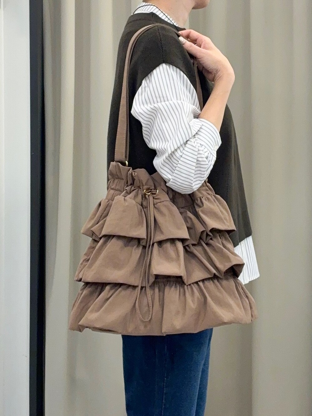 ブルー系のデニムパンツ、グレー系のパンプス、ゴールド系のネックレスを着用したレディースの秋コーディネートの4枚目の写真