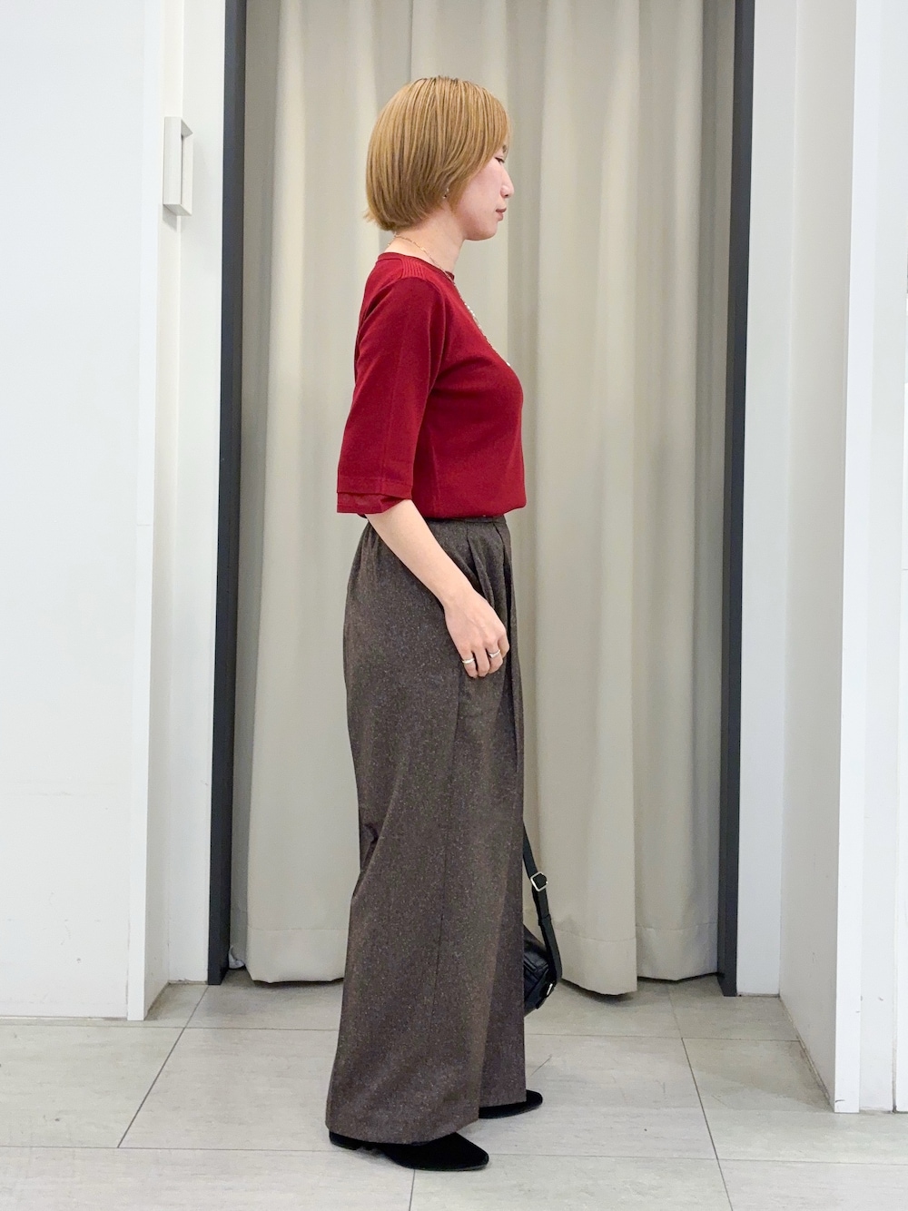 レッド系のニット/セーター、ブラウン系のその他パンツ、ブラック系のショルダーバッグを着用したレディースの秋コーディネートの2枚目の写真