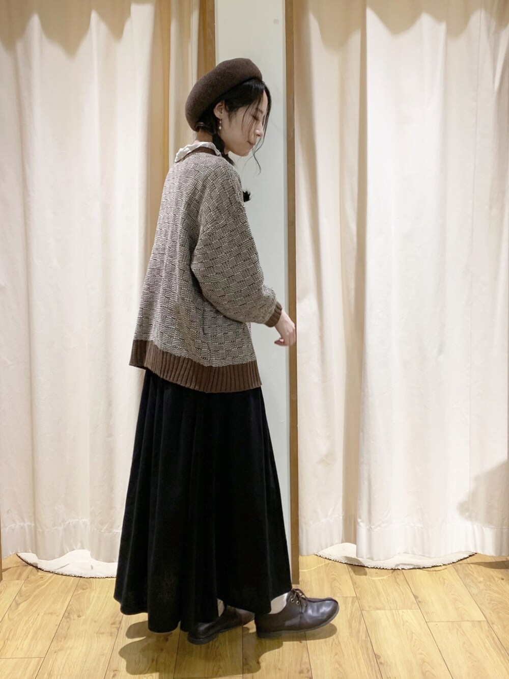 ブラウン系のニット/セーター、ブラック系のスカート、ホワイト系のシャツ/ブラウスを着用したレディースの秋コーディネートの2枚目の写真