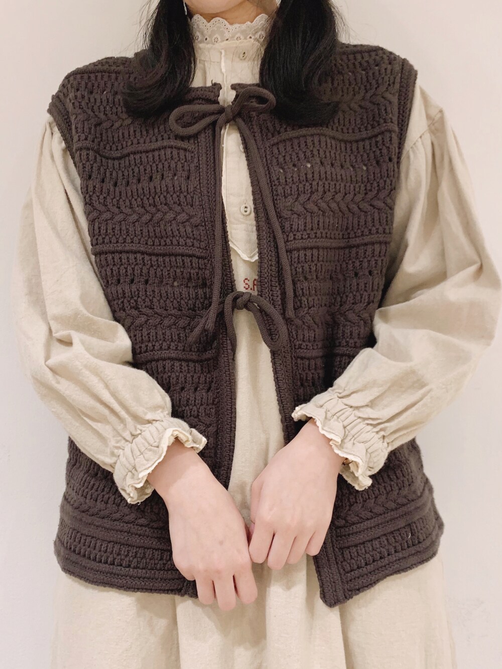 ブラウン系のベスト、ホワイト系のワンピース、ベージュ系のTシャツ/カットソーを着用したレディースの冬コーディネートの5枚目の写真