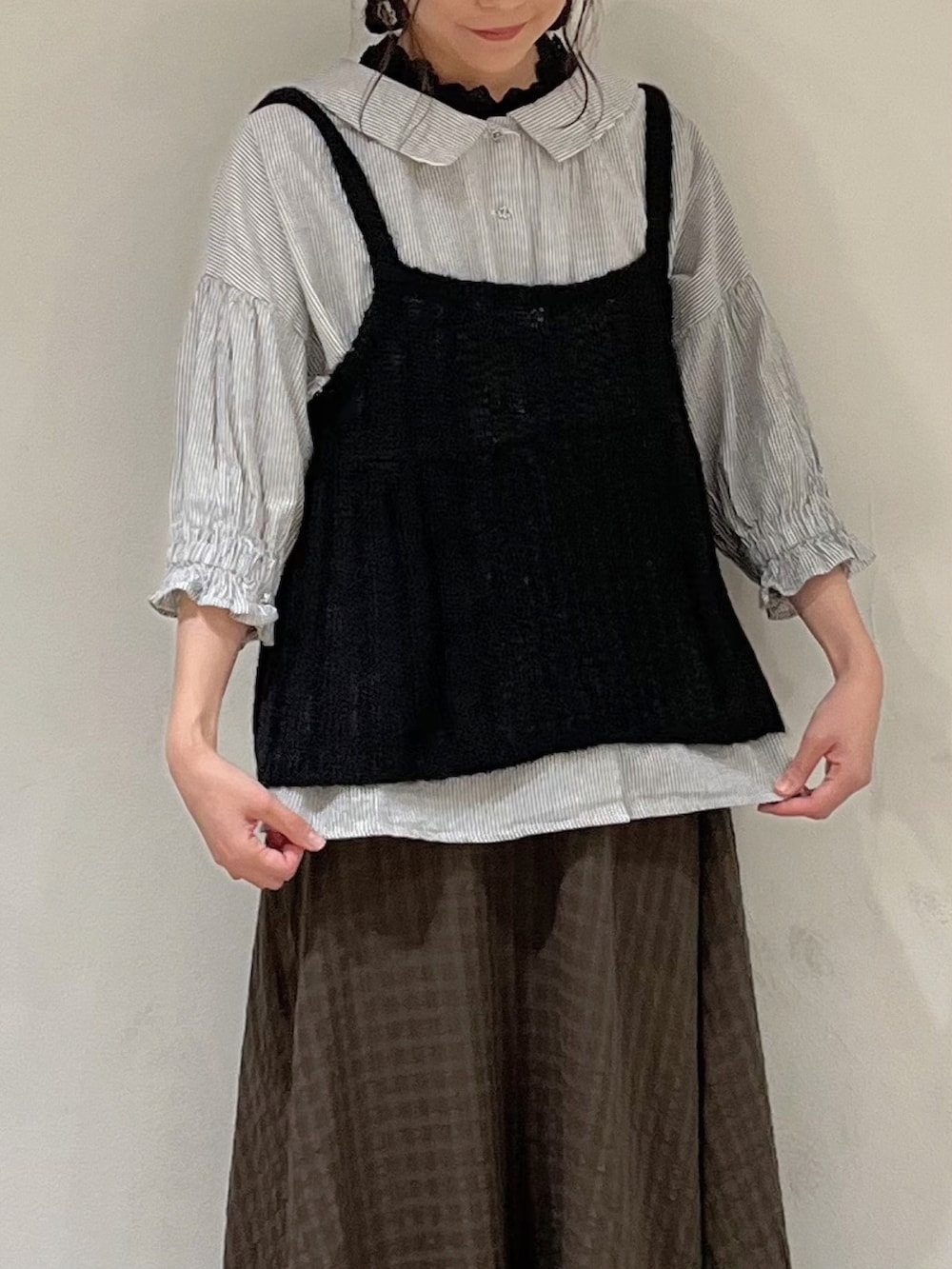 ブラック系のニット/セーター、グレー系のシャツ/ブラウス、ブラック系のタンクトップを着用したレディースの秋コーディネートの5枚目の写真