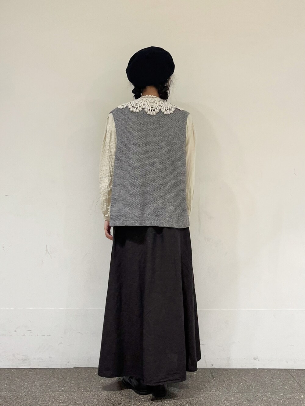 グレー系のベスト、ベージュ系のシャツ/ブラウス、グレー系のスカートを着用したレディースの秋コーディネートの3枚目の写真