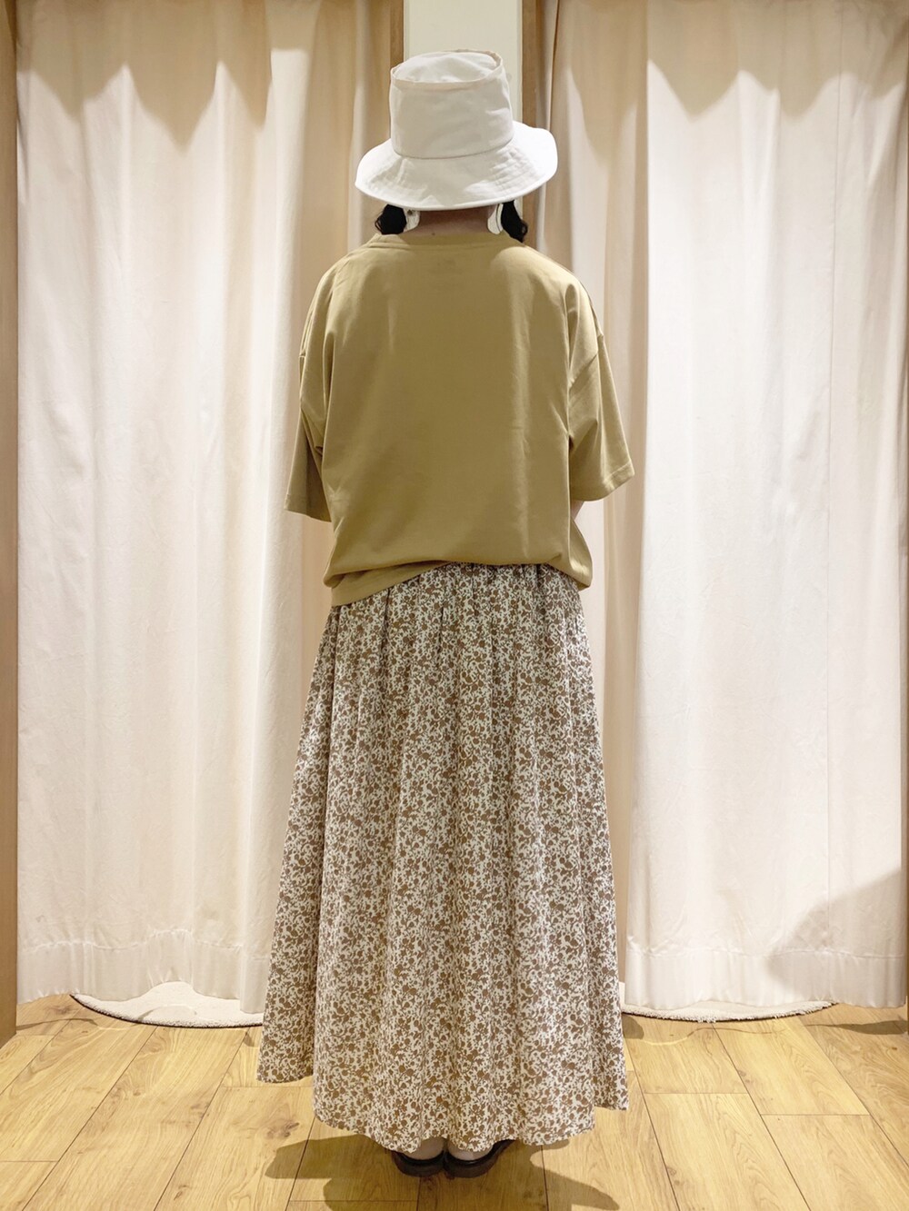 イエロー系のTシャツ/カットソー、オレンジ系のスカート、ホワイト系のTシャツ/カットソーを着用したレディースの春コーディネートの2枚目の写真