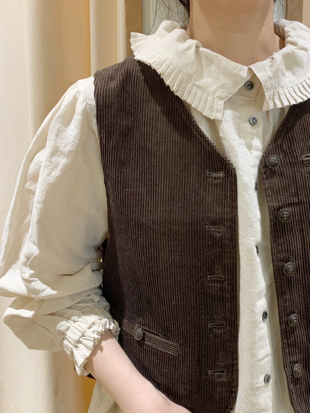 ブラウン系のベスト、ブラウン系のその他パンツ、ホワイト系のシャツ/ブラウスを着用したレディースの秋コーディネートの5枚目の写真