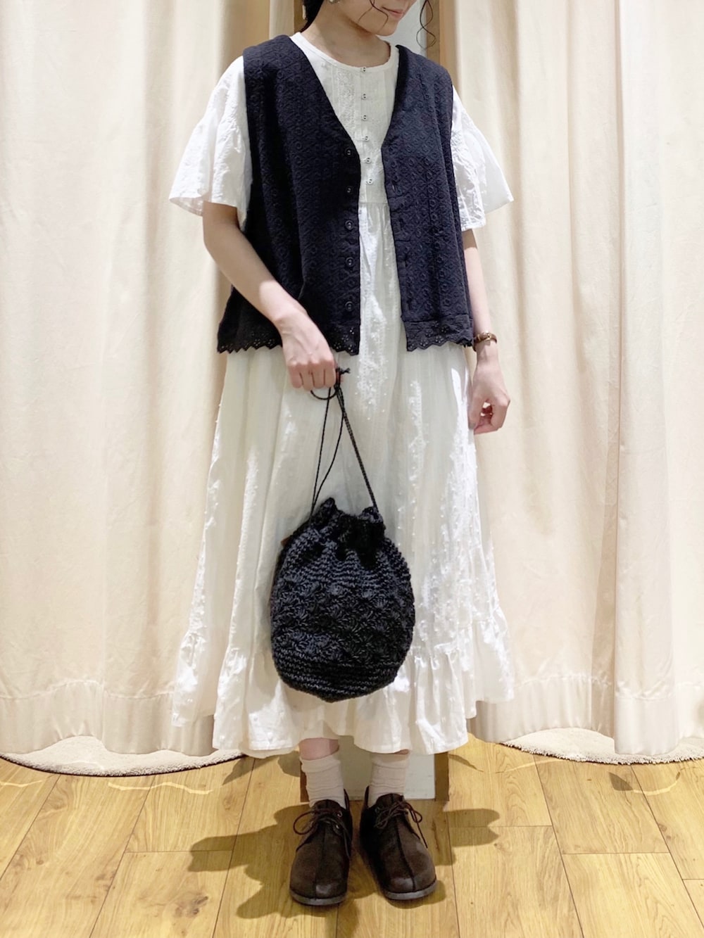 グレー系のベスト、ホワイト系のワンピース、ホワイト系のTシャツ/カットソーを着用したレディースの春コーディネートの2枚目の写真