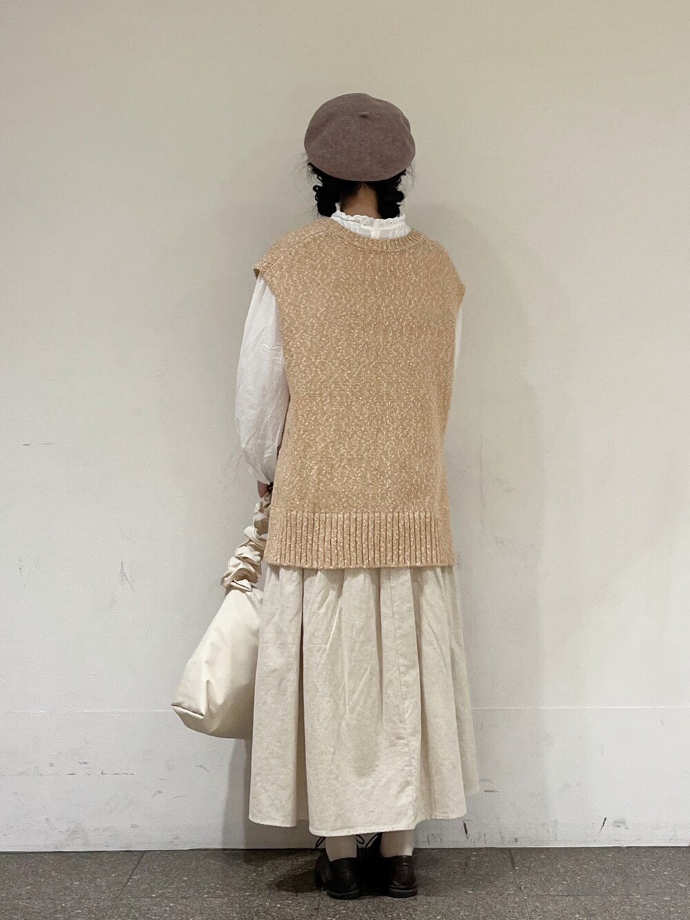 ベージュ系のベスト、ベージュ系のスカート、ホワイト系のハンドバッグを着用したレディースの冬コーディネートの4枚目の写真