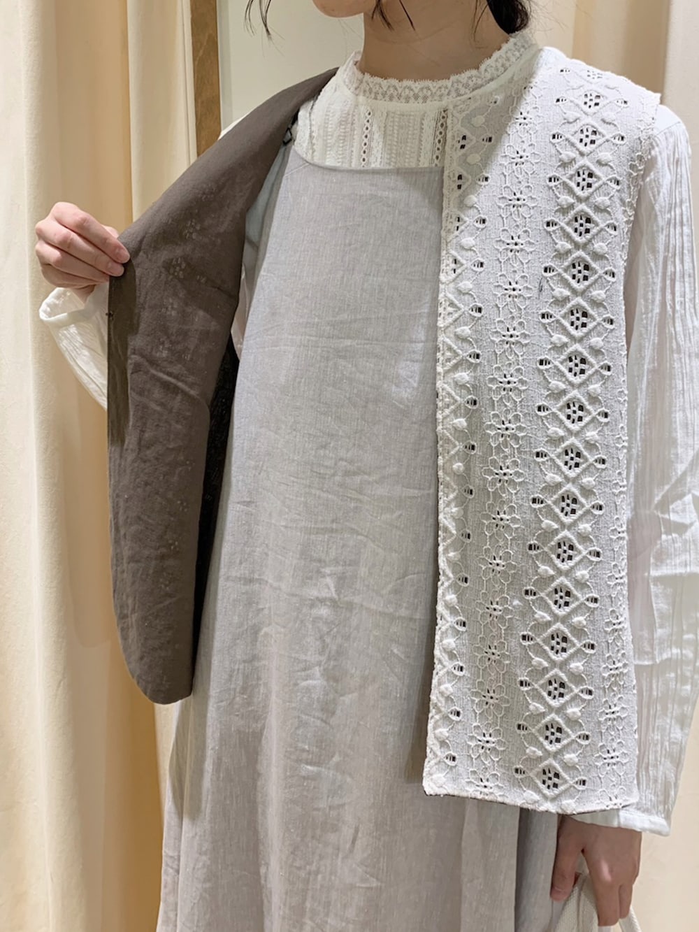 グレー系のワンピース、ホワイト系のベスト、ホワイト系のスカートを着用したレディースの春コーディネートの5枚目の写真