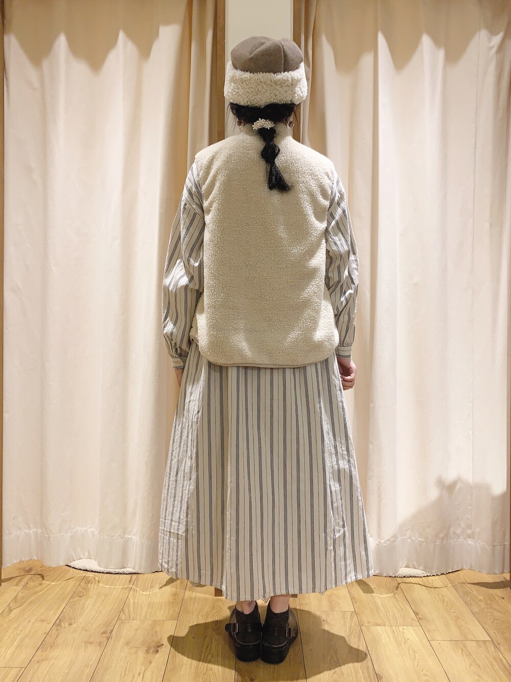 ホワイト系のベスト、ホワイト系のワンピース、ベージュ系のスカートを着用したレディースの秋コーディネートの2枚目の写真