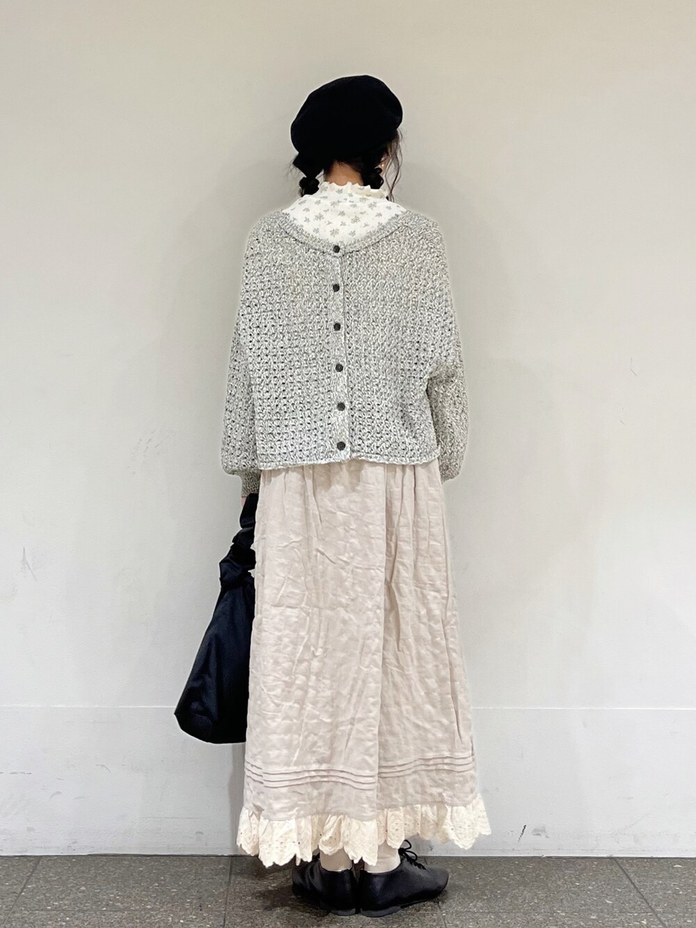 ブルー系のTシャツ/カットソー、ブラック系のカーディガン/ボレロ、ベージュ系のスカートを着用したレディースの冬コーディネートの4枚目の写真