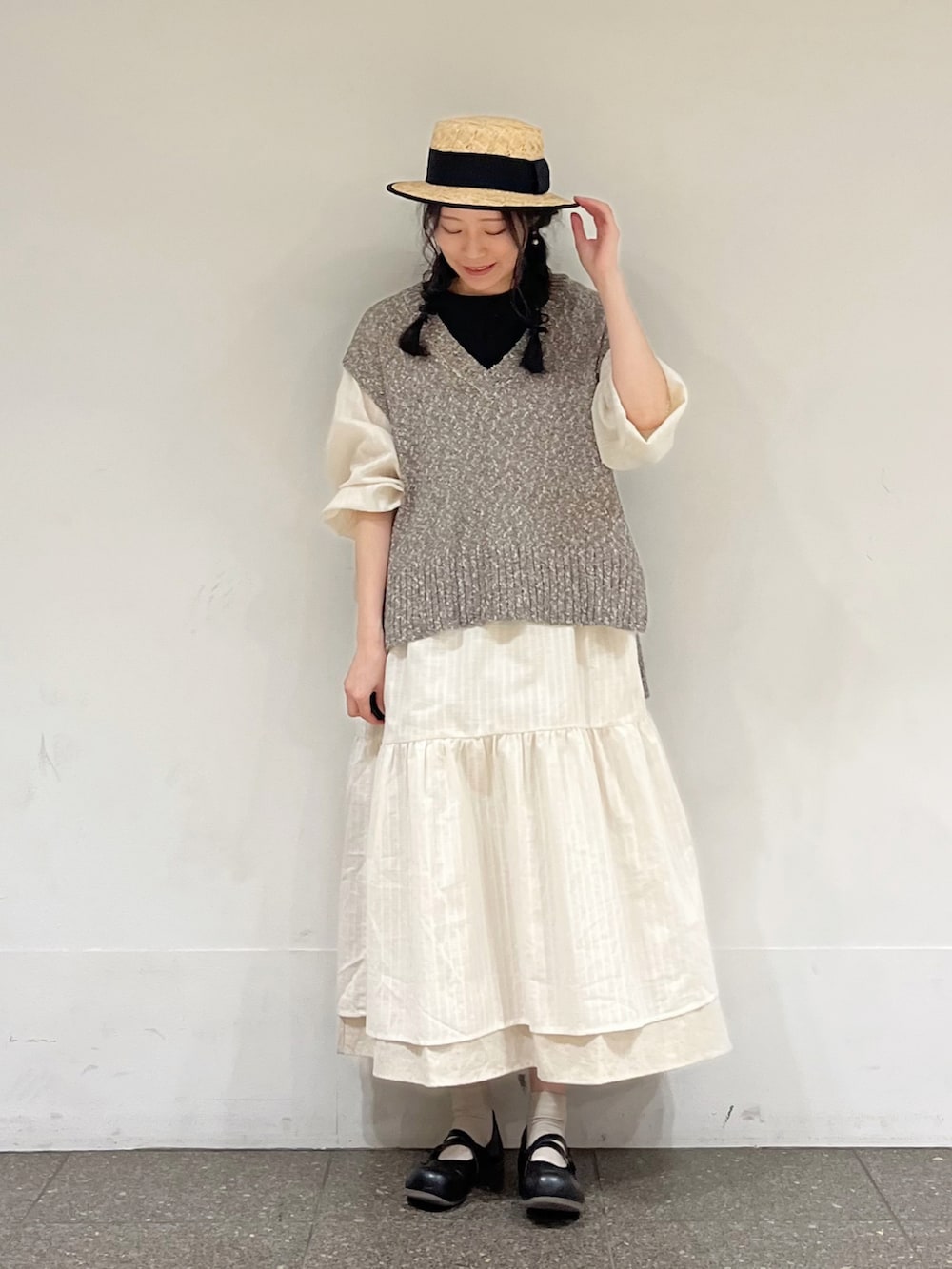 ブラウン系のベスト、ホワイト系のワンピース、ベージュ系のスカートを着用したレディースの冬コーディネートの2枚目の写真