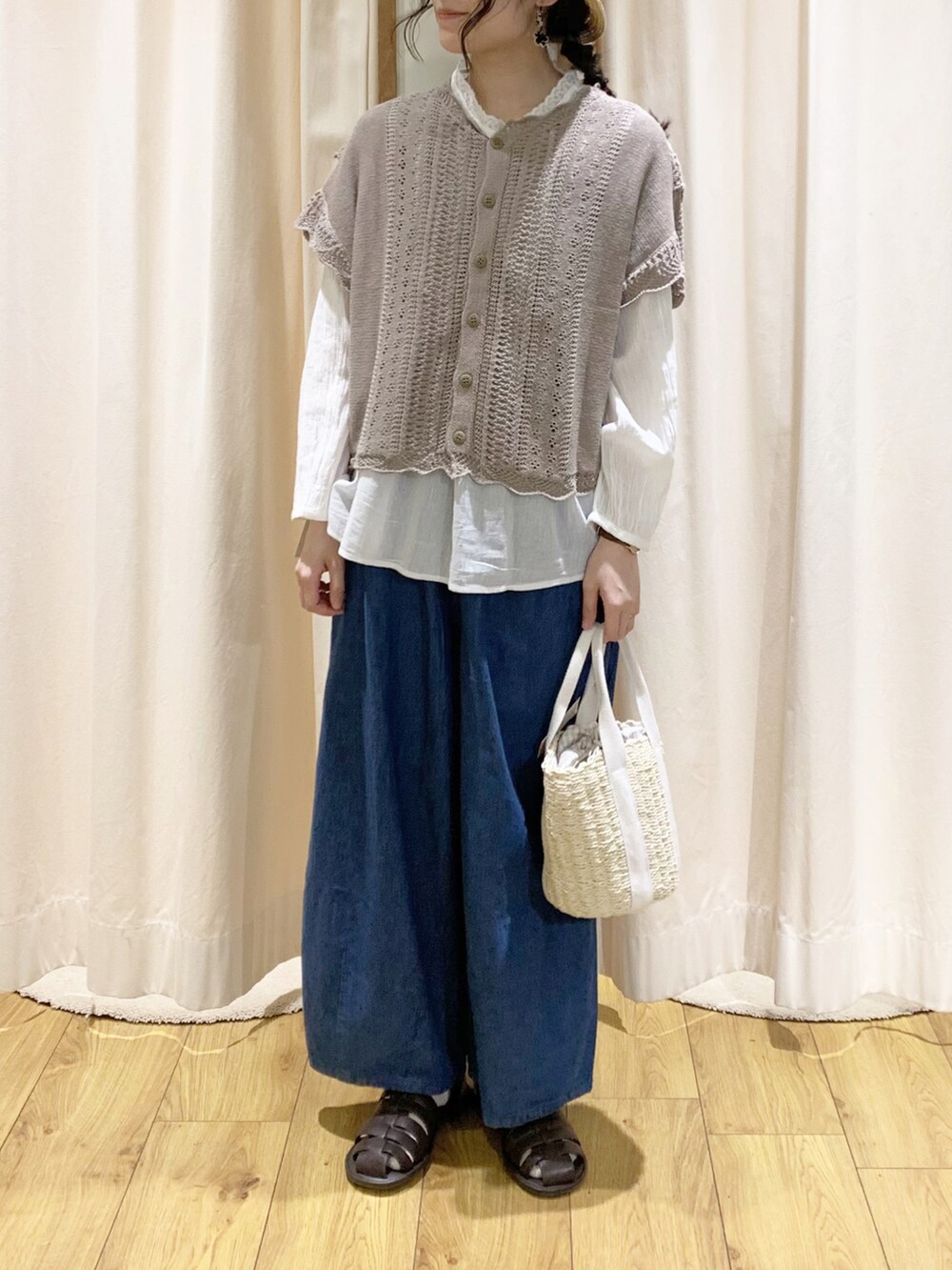 ブラウン系のベスト、ホワイト系のシャツ/ブラウス、ブルー系のデニムパンツを着用したレディースの春コーディネートの2枚目の写真