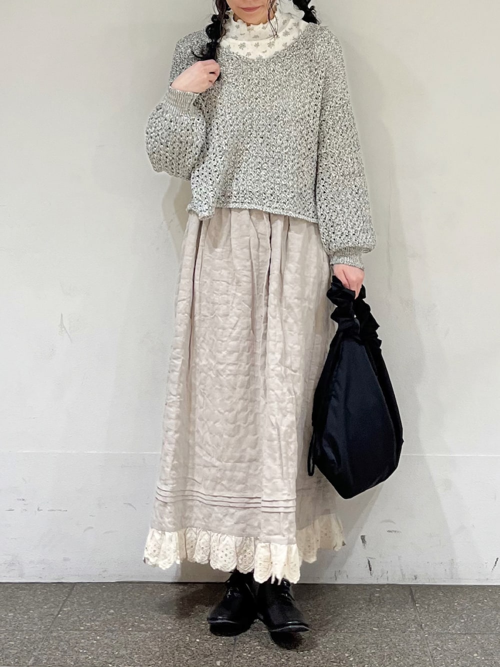 ブルー系のTシャツ/カットソー、ブラック系のカーディガン/ボレロ、ベージュ系のスカートを着用したレディースの冬コーディネートの2枚目の写真