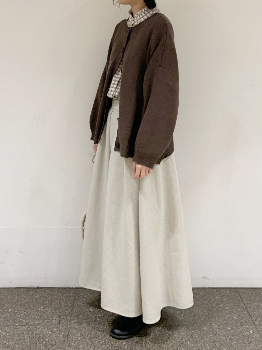 ブラウン系のニット/セーター、ベージュ系のシャツ/ブラウス、ベージュ系のスカートを着用したレディースの冬コーディネートの2枚目の写真