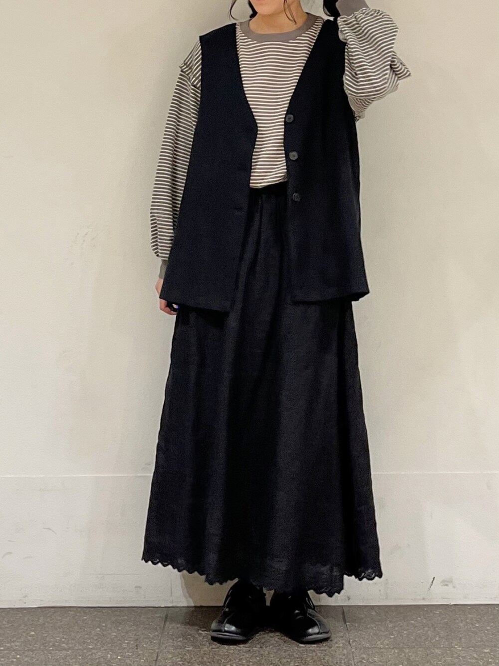 ブラウン系のTシャツ/カットソー、グレー系のベスト、ブラック系のスカートを着用したレディースの春コーディネートの4枚目の写真