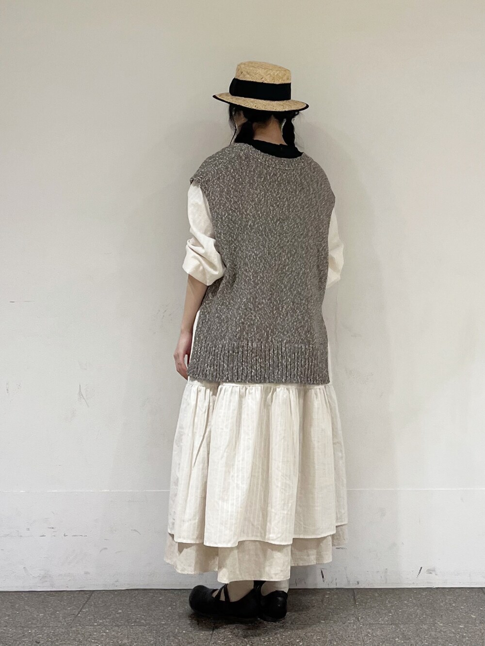 ブラウン系のベスト、ホワイト系のワンピース、ベージュ系のスカートを着用したレディースの冬コーディネートの4枚目の写真